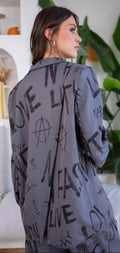 Woman wearing a gray shirt with text and symbols, standing in a room with plants.